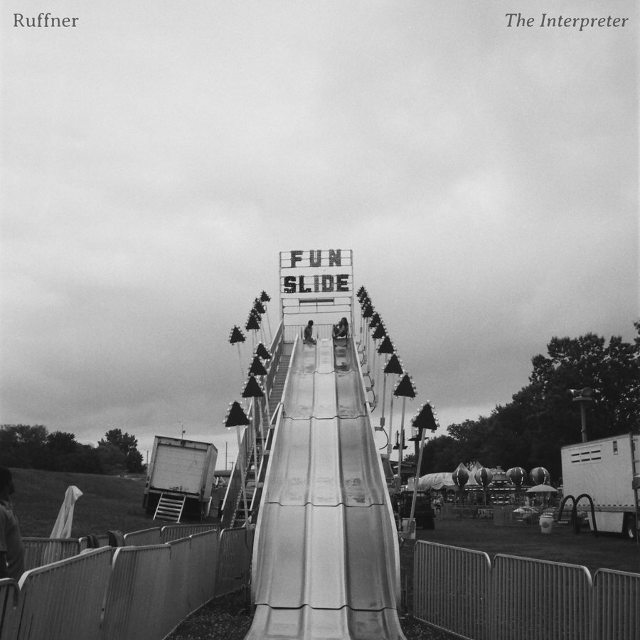 Ruffner — The Interpreter. A black and white photograph of a fairground fun slide under an overcast sky.